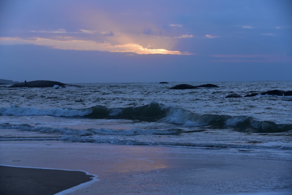 ocean waves crashing on shore during sunset