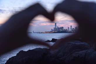 A vibrant illustration showing a heart transforming into a blood drop surrounded by city skyline at sunset.