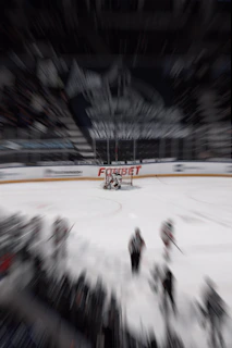 Action shot of a player gripping a hockey stick mid-swing on the ice, with motion blur emphasizing speed and power.
