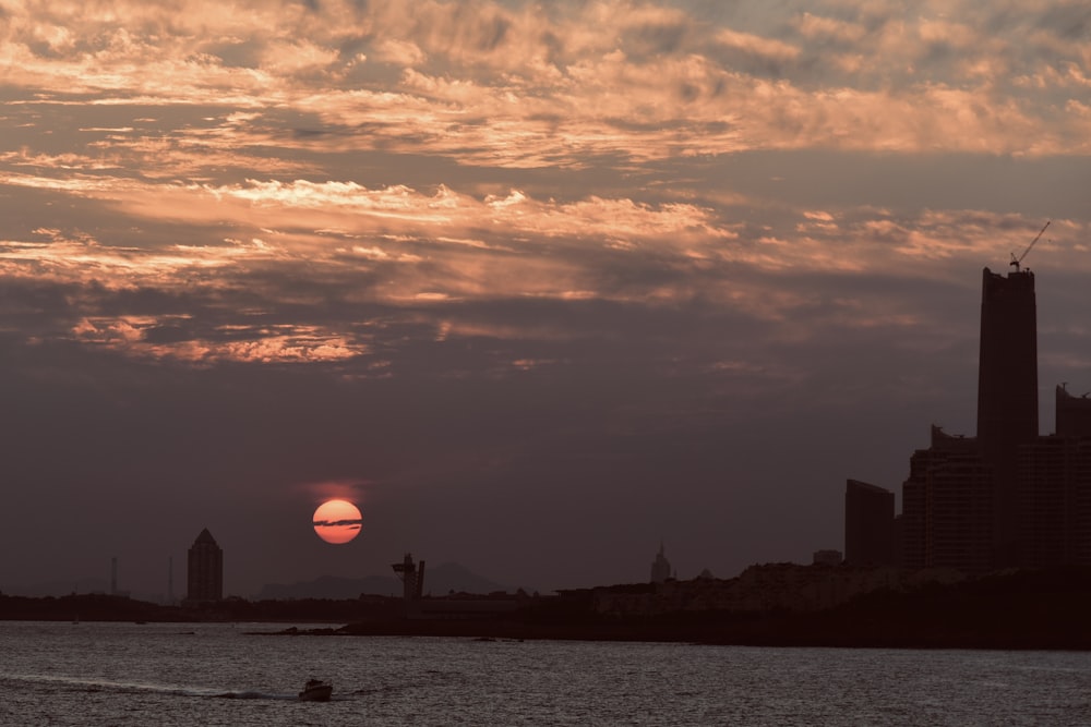 silhouette of building near body of water during sunset