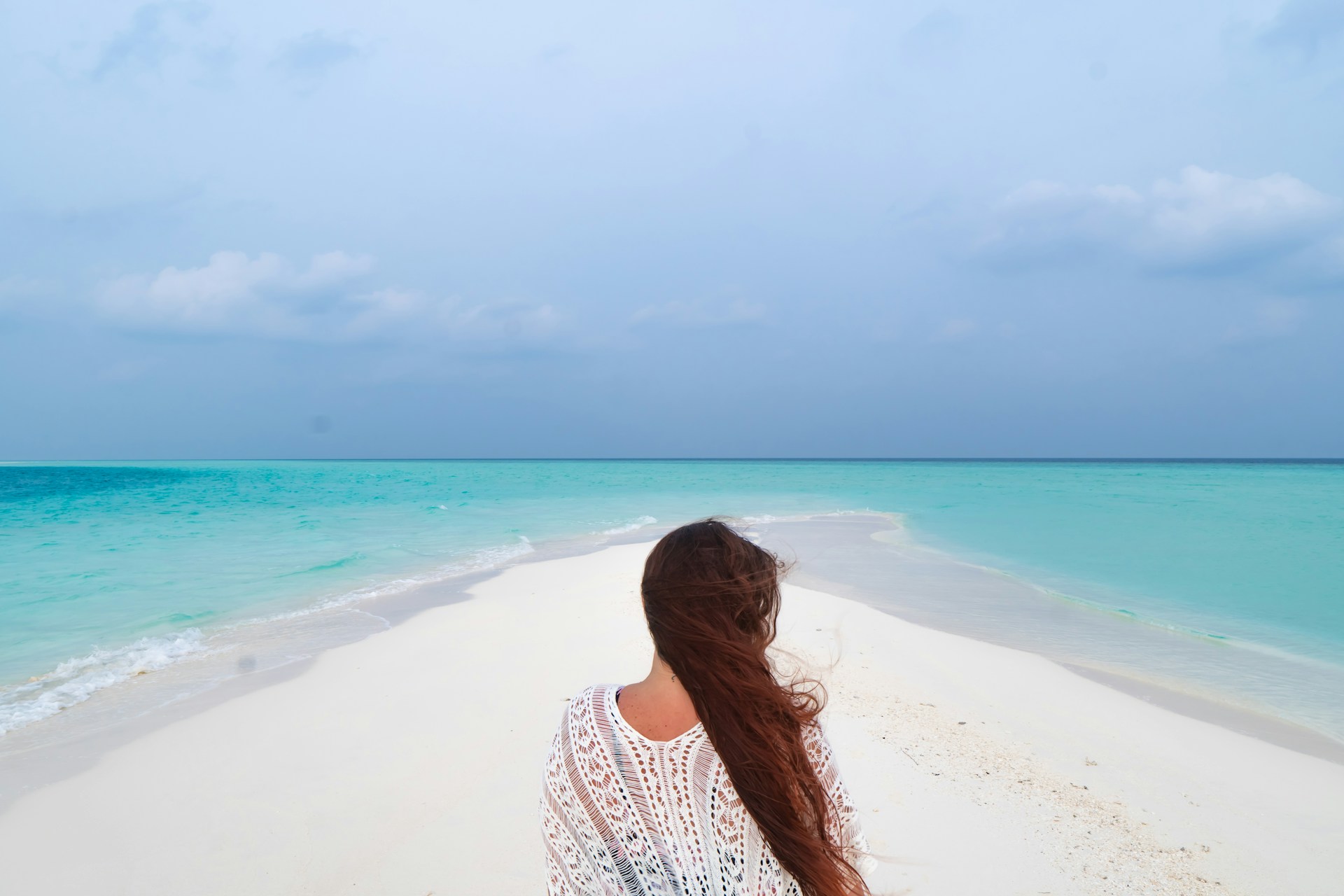 woman in white and black polka dot shirt standing on beach during daytime
