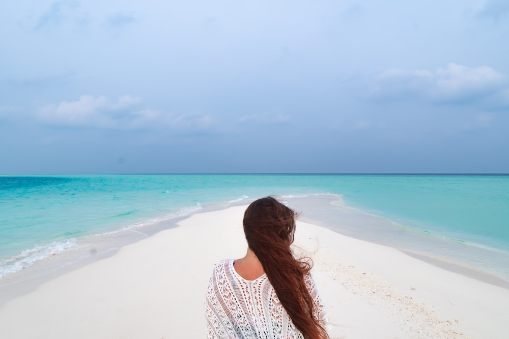 woman in white and black polka dot shirt standing on beach during daytime