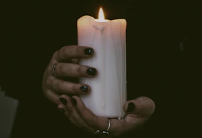 person holding white pillar candle