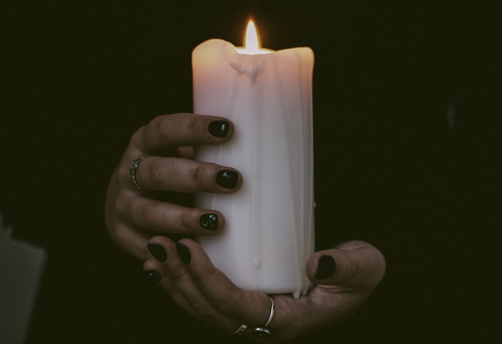 person holding white pillar candle