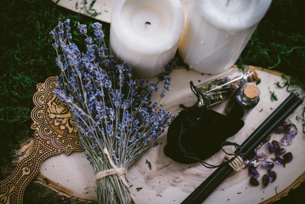 white pillar candle beside silver and black hair brush