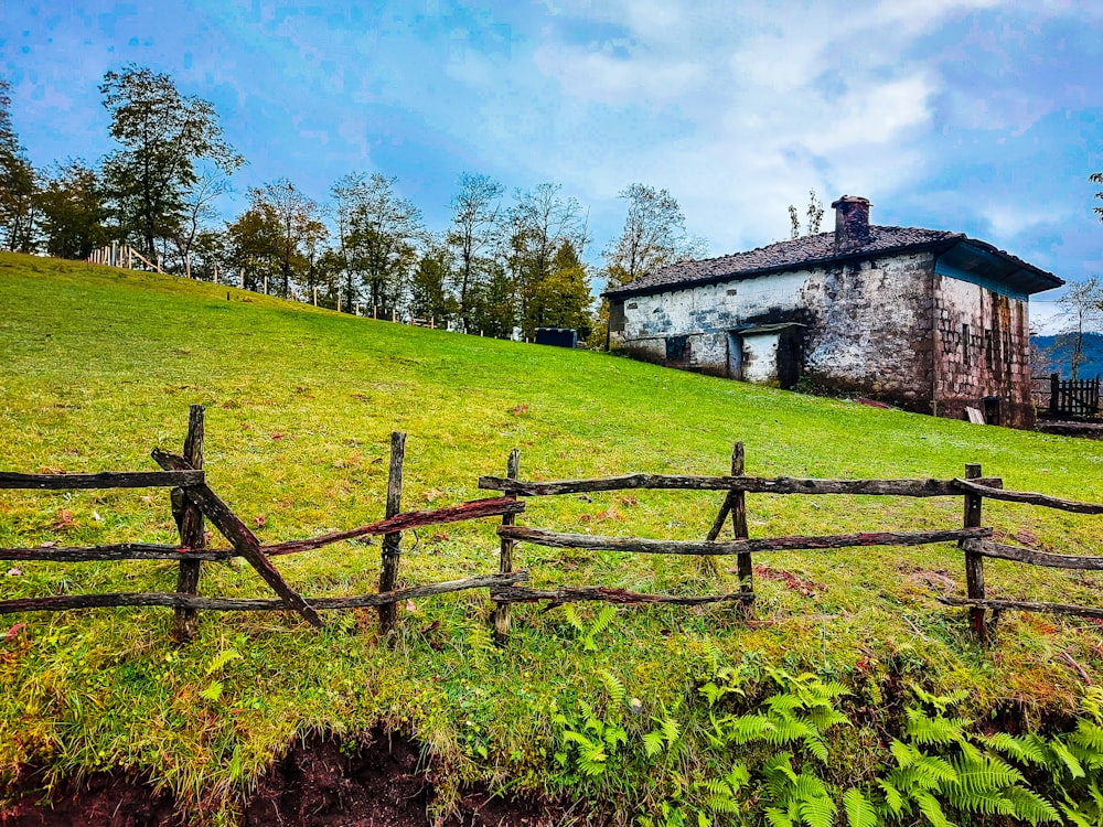 brown wooden fence on green grass field near white concrete building during daytime