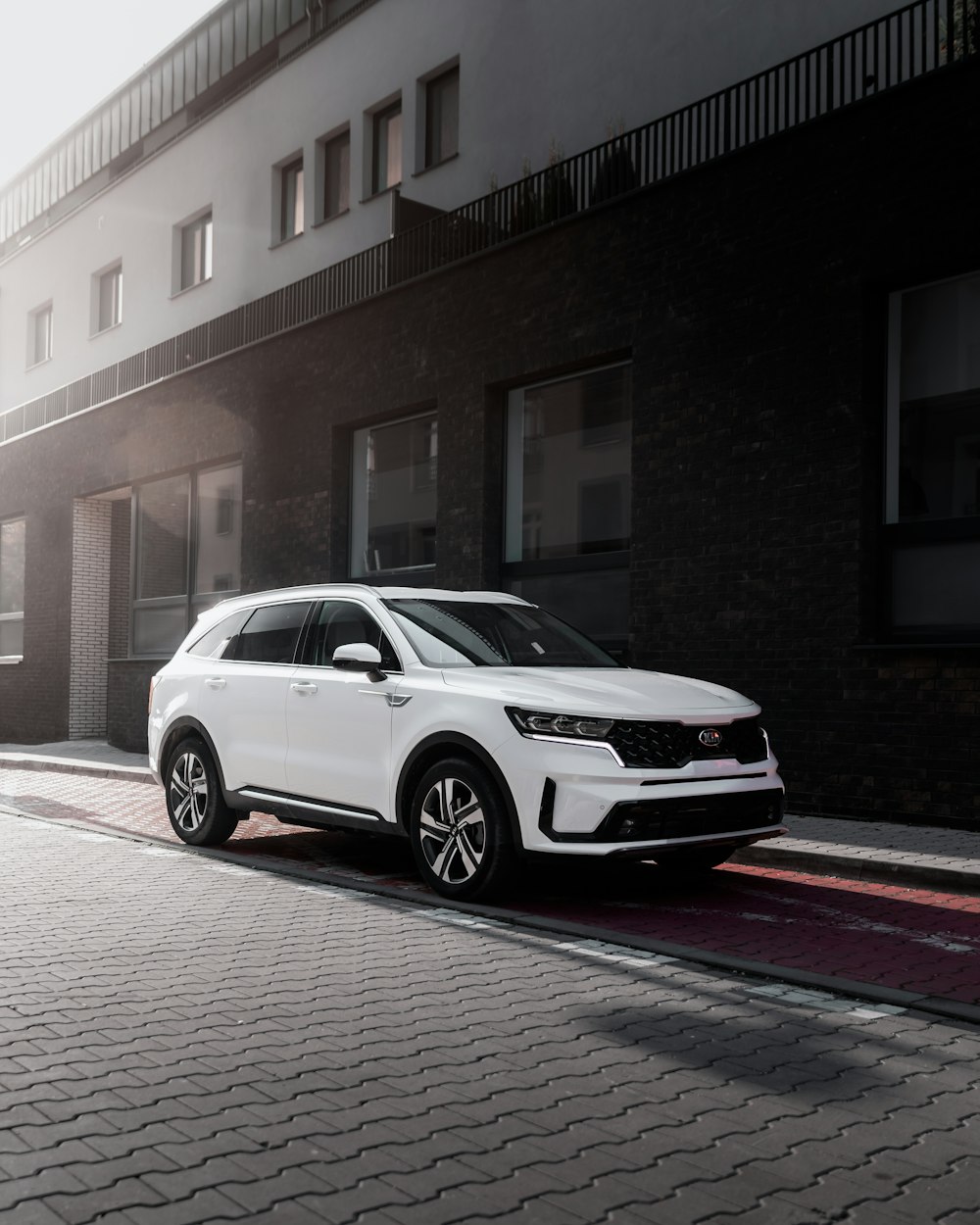 white suv parked beside brown concrete building