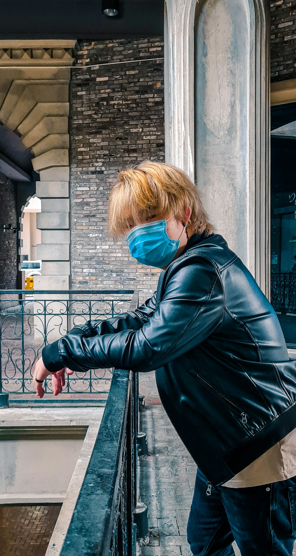 woman in black leather jacket standing beside gray concrete wall during daytime