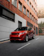 red car parked beside white concrete building during daytime