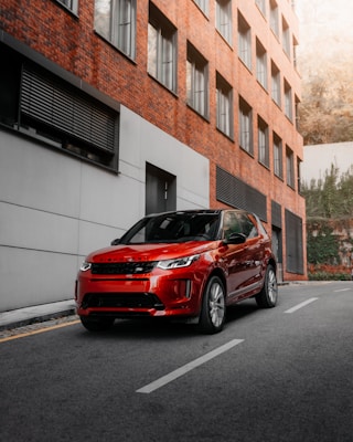 red car parked beside white concrete building during daytime