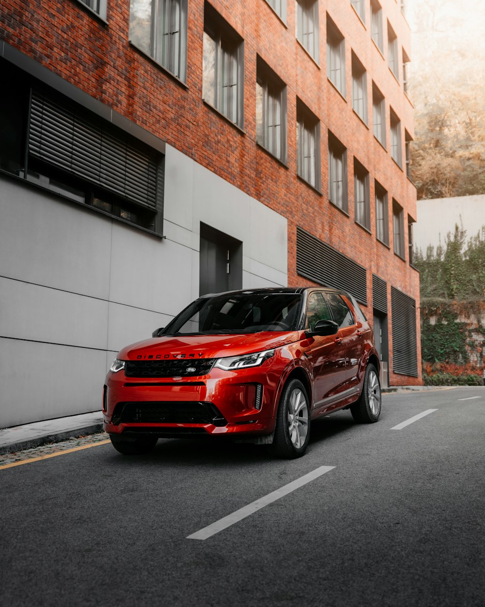 red car parked beside white concrete building during daytime