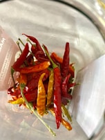 A vibrant display of assorted chili peppers next to bottles of spicy sauces with handcrafted labels.