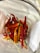A collection of vibrant red and yellow chili peppers are gathered together inside a clear glass container. The peppers are variously shaped and sized, with smooth skin and green stems still attached. The lighting highlights their glossy texture, creating a lively and colorful display.