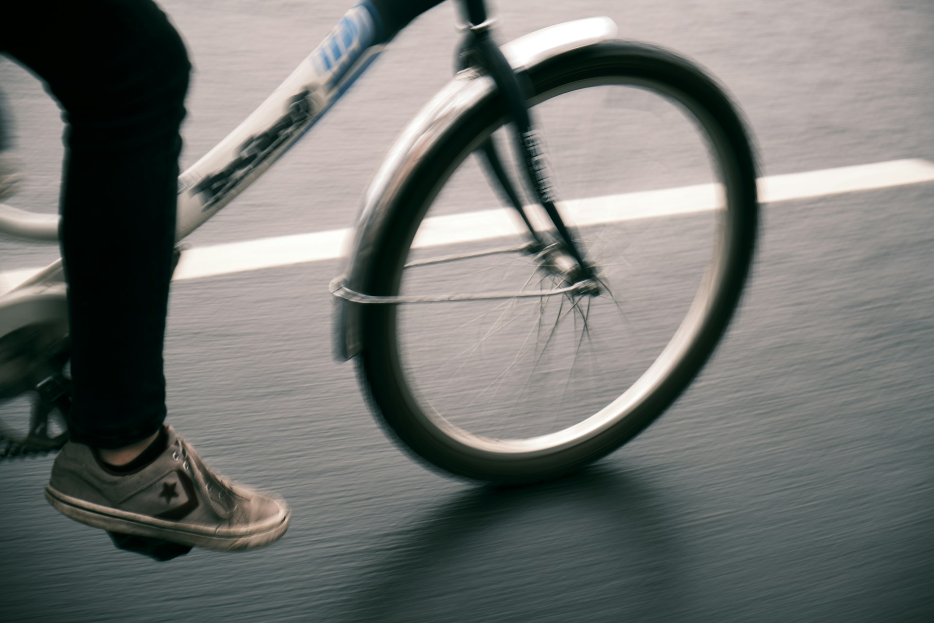Close-up of bicycle wheels spinning rapidly on a smooth road, capturing dynamic motion.