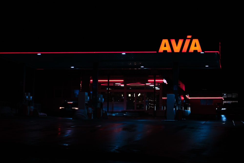 a neon sign above a gas station at night