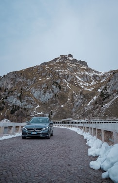 A sleek black limousine parked against the snowy Aspen mountain backdrop at sunset.