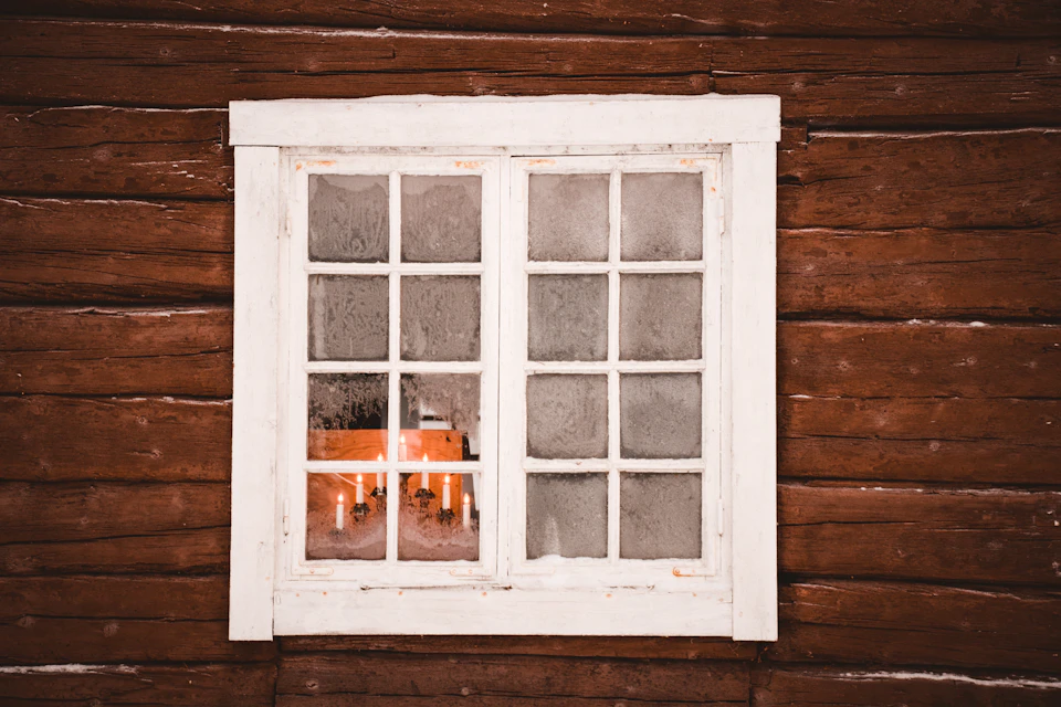 White window with two panes partially open, revealing a red bucket and yellow flower pot