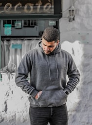 man in gray hoodie standing near white wall