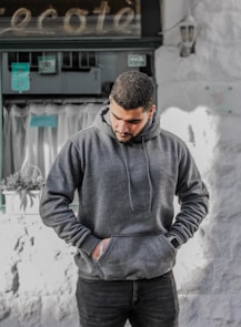 man in gray hoodie standing near white wall