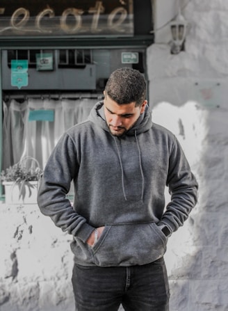 man in gray hoodie standing near white wall