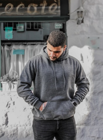 man in gray hoodie standing near white wall