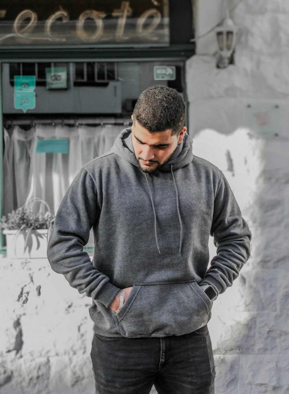 man in gray hoodie standing near white wall
