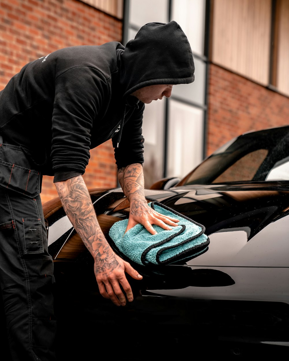 man in black long sleeve shirt and black pants sitting on black car