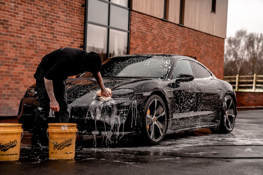 Detailer hand washing a dark Porsche with premium foam and microfiber