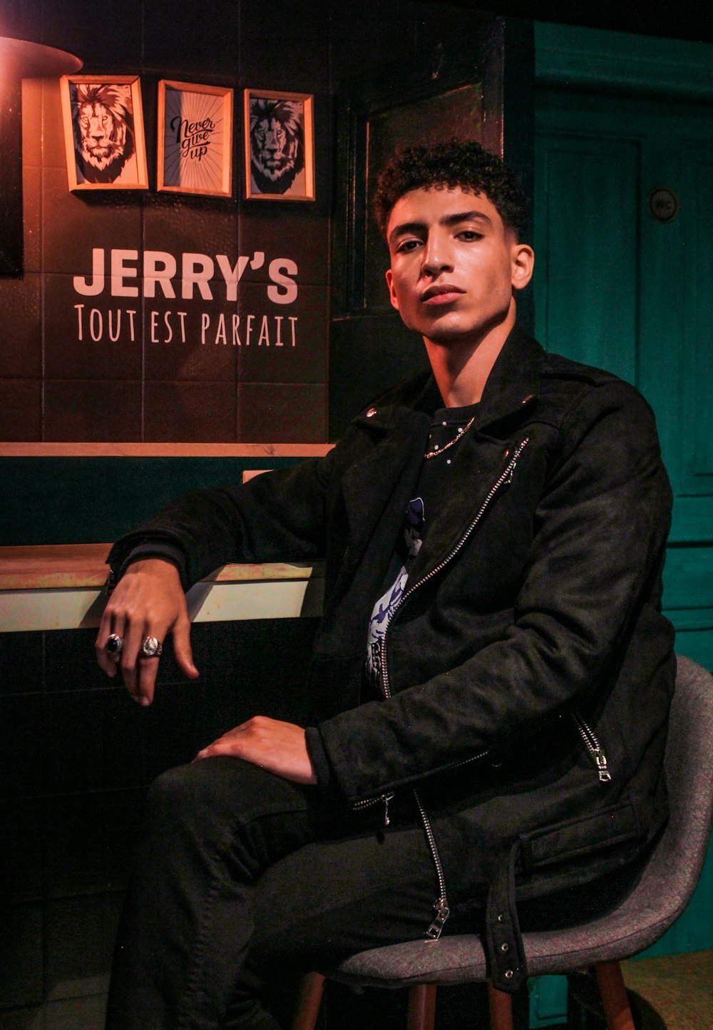 man in black leather jacket sitting on chair