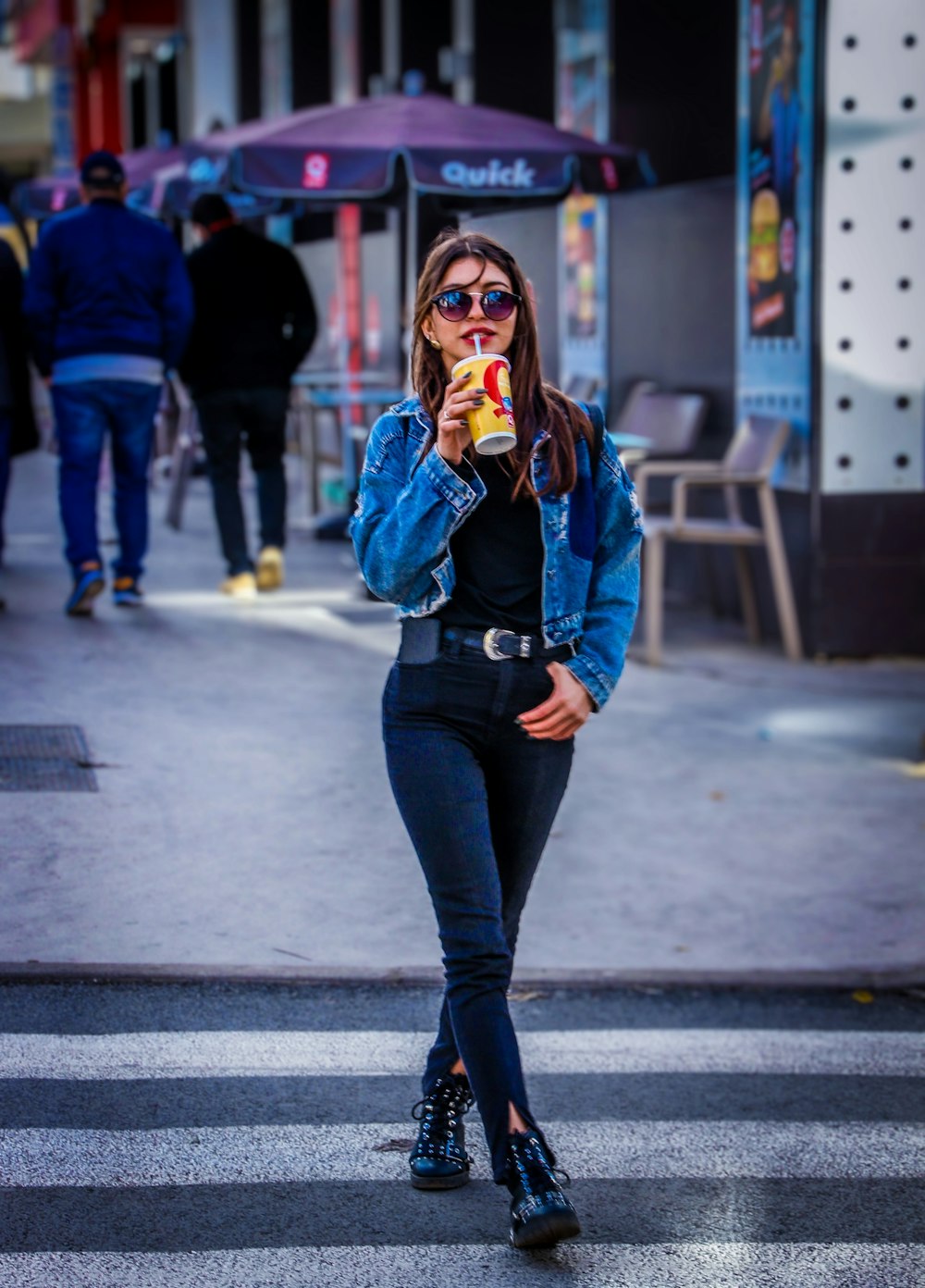 woman in blue denim jacket and black pants standing on sidewalk during daytime