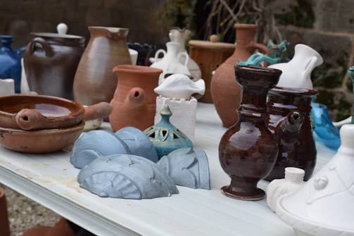 Ceramic pieces glazed with earth tones arranged on a wooden table.