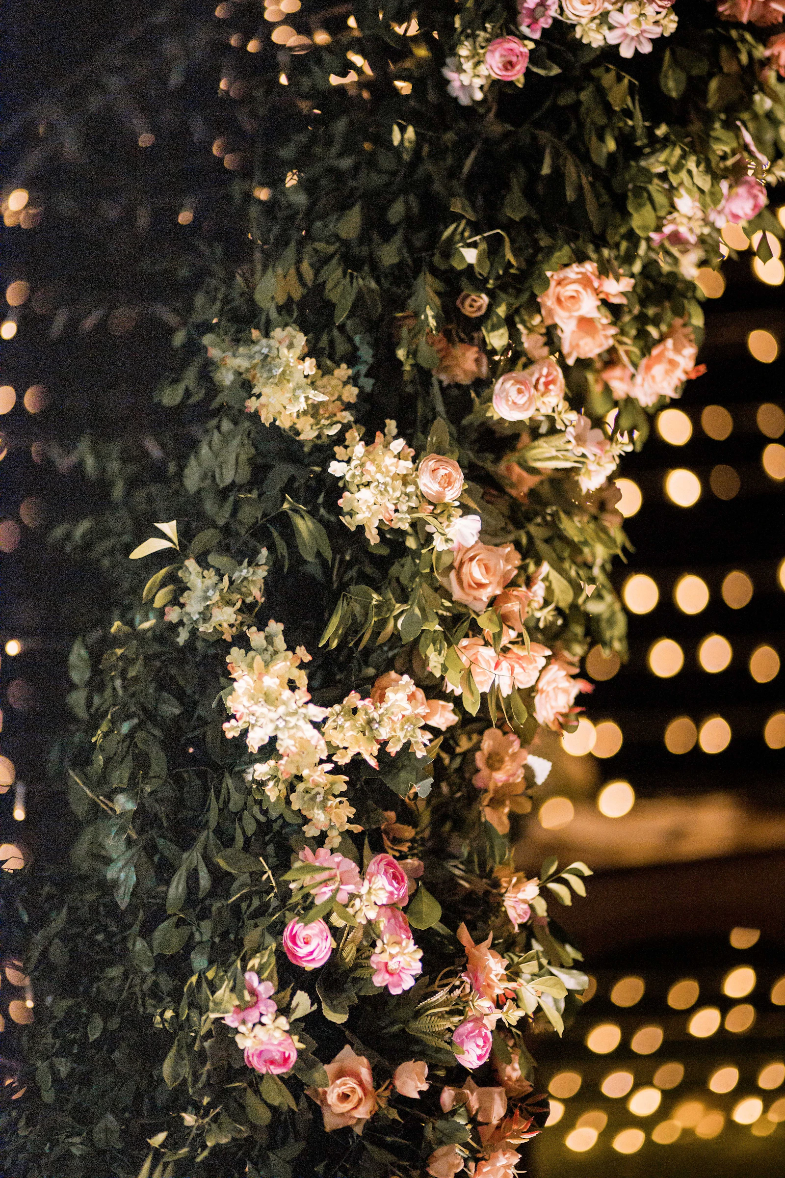 A floral installation lit from behind at an evening reception.