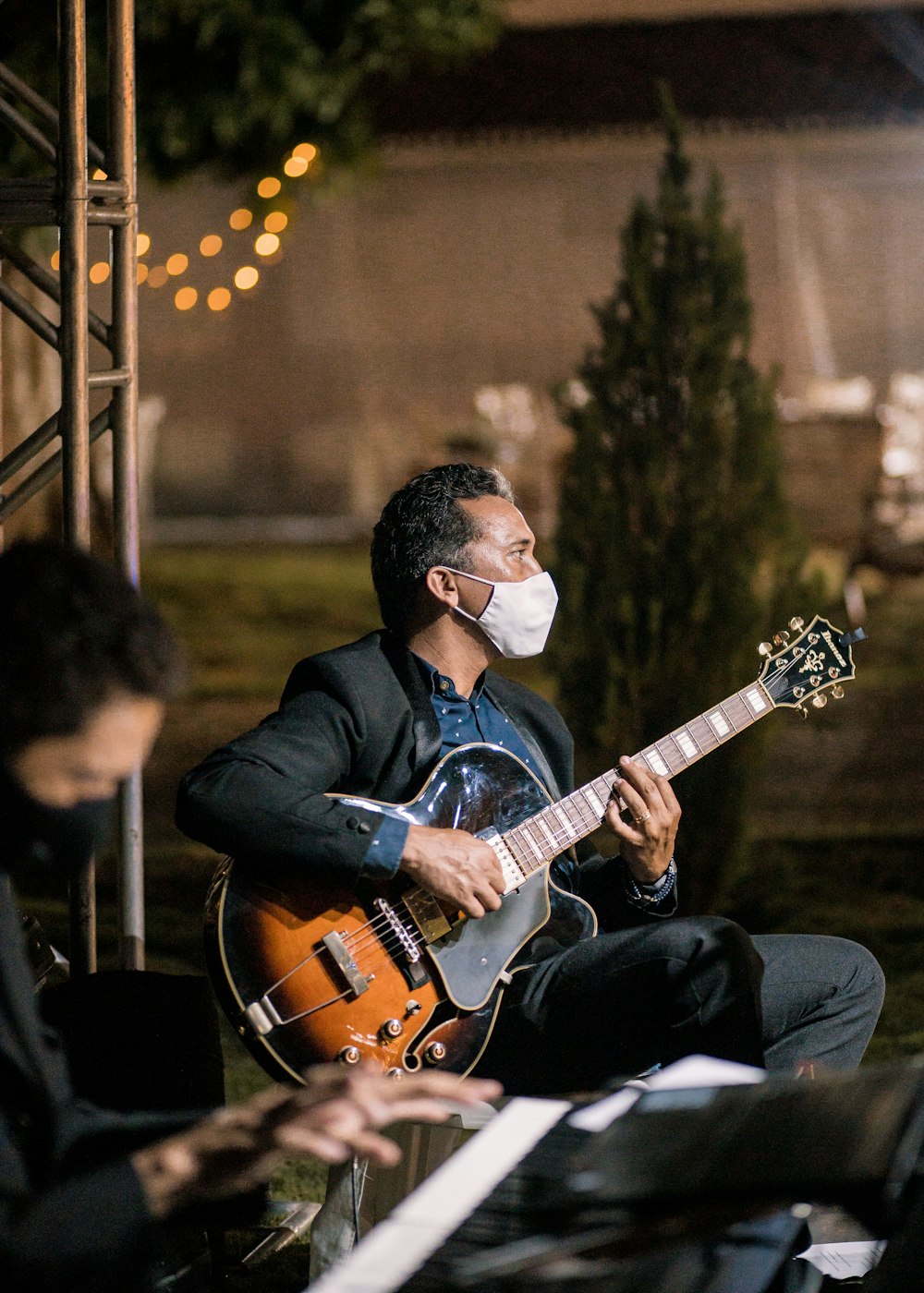 man in black jacket playing brown electric guitar