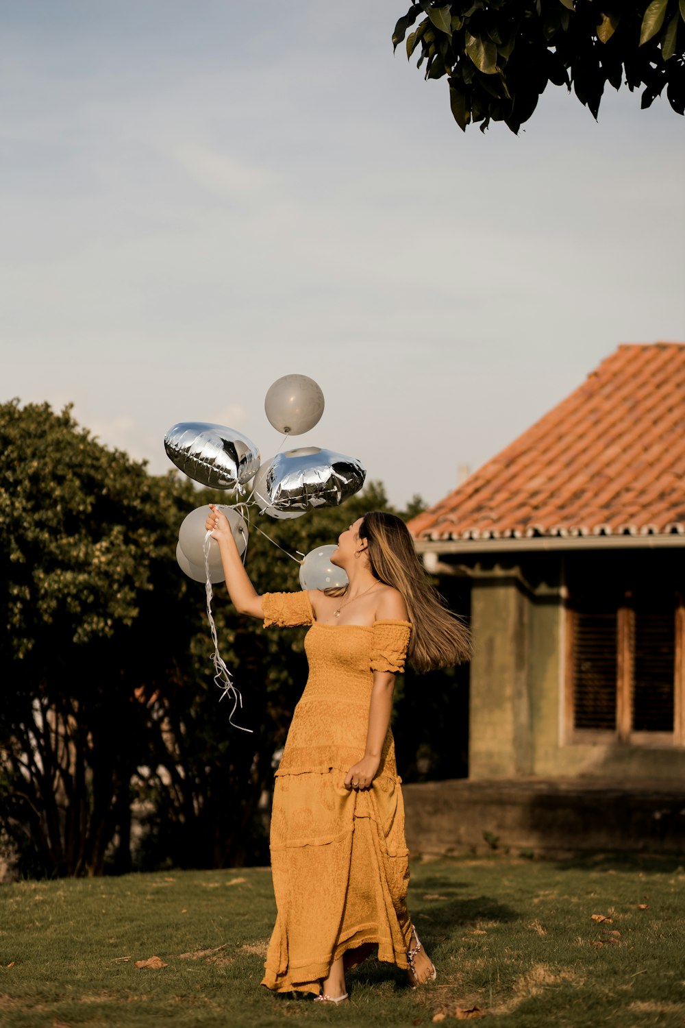 woman in brown dress holding white balloons