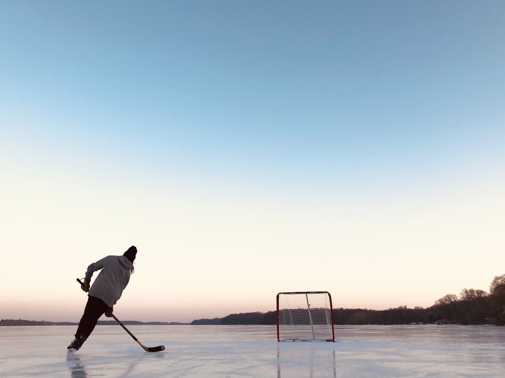 man in white shirt and black pants holding white stick standing on snow covered ground during