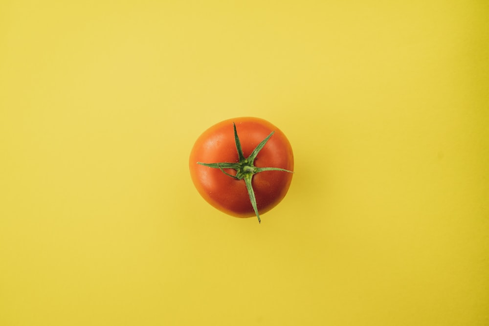 orange Tomate auf gelber Oberfläche