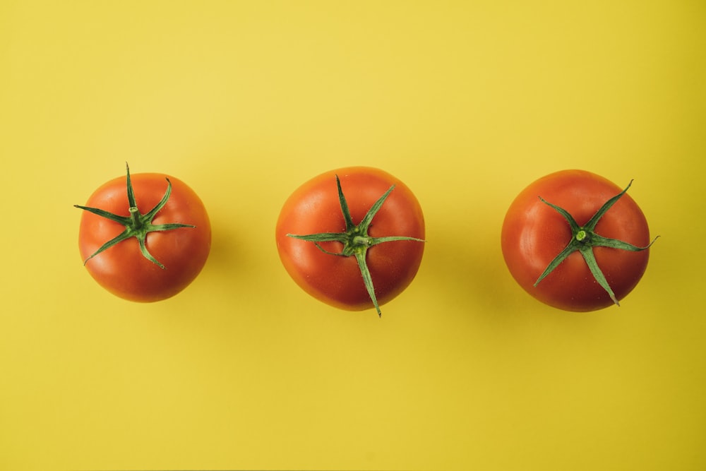 3 tomates rouges sur fond jaune