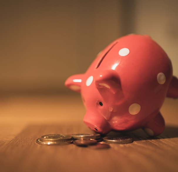 pink pig coin bank on brown wooden table