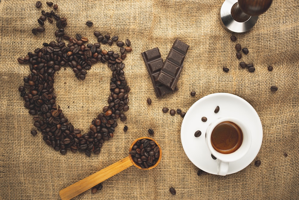 coffee beans on white ceramic mug beside coffee beans