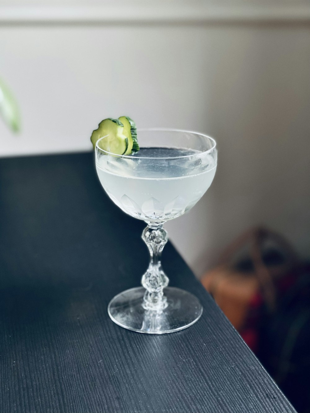 clear cocktail glass with green fruit on brown wooden table