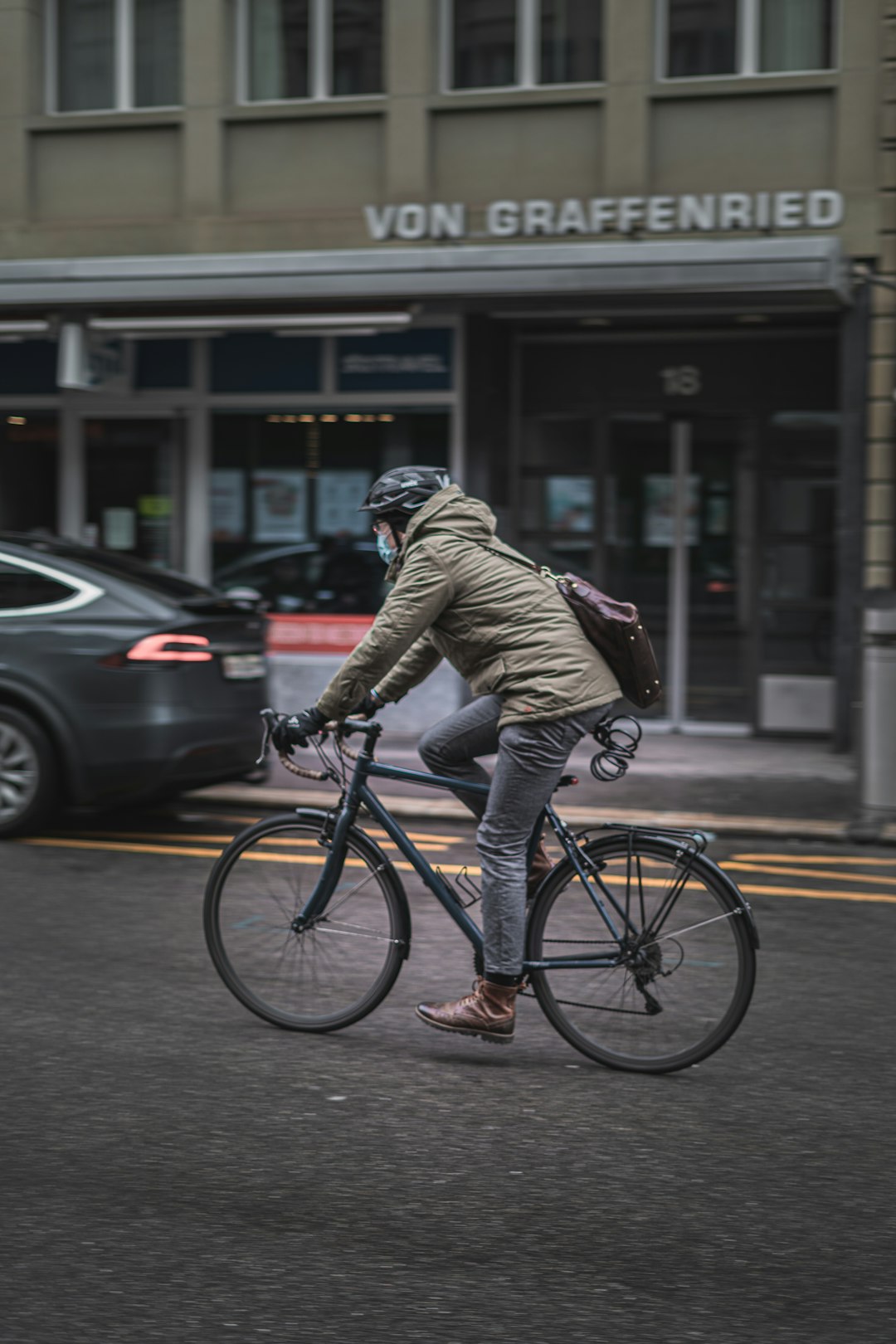 man in brown jacket riding bicycle on road during daytime