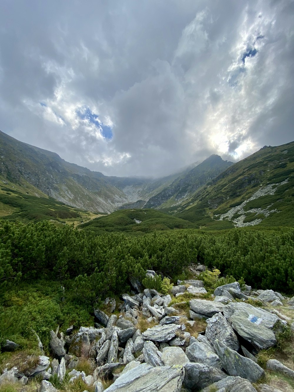 green grass field and mountain under white clouds and blue sky during daytime