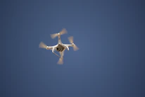 Close-up of a Flyfrogg drone’s intricate propellers spinning mid-flight against a clear blue sky.