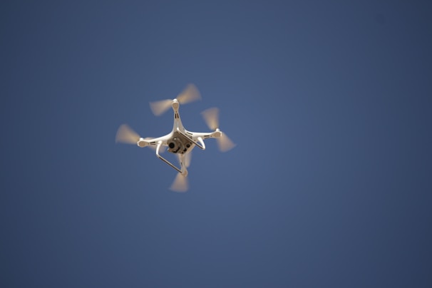 A high-speed FPV drone soaring through a clear blue sky.