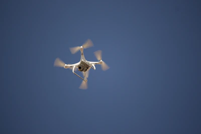 Close-up of a Flyfrogg drone’s intricate propellers spinning mid-flight against a clear blue sky.