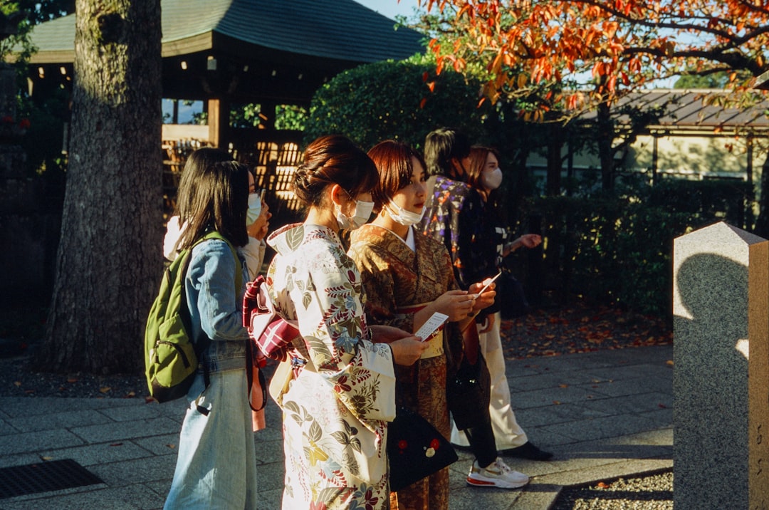 2 women in kimono standing on sidewalk during daytime