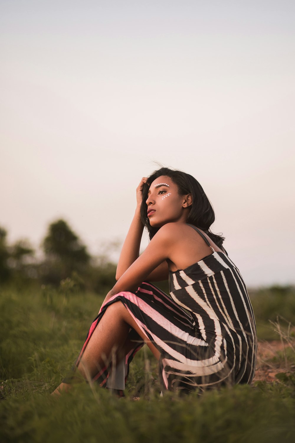 woman in black and white stripe dress standing on green grass field during daytime