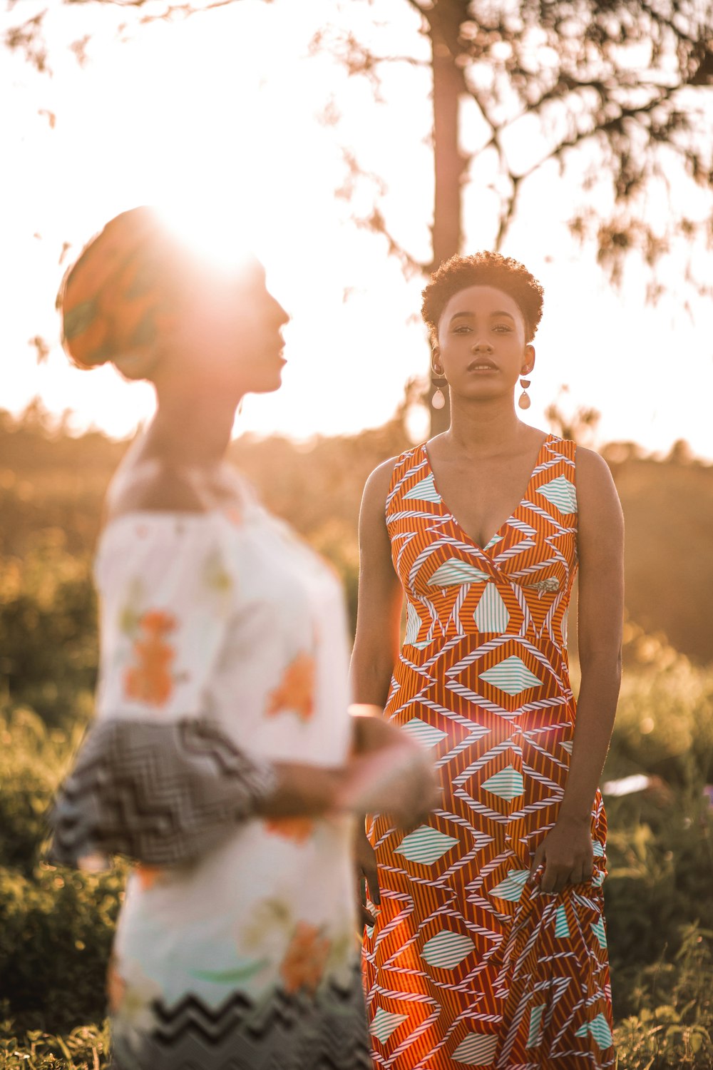 woman in white orange and yellow floral tank top standing beside woman in white and orange