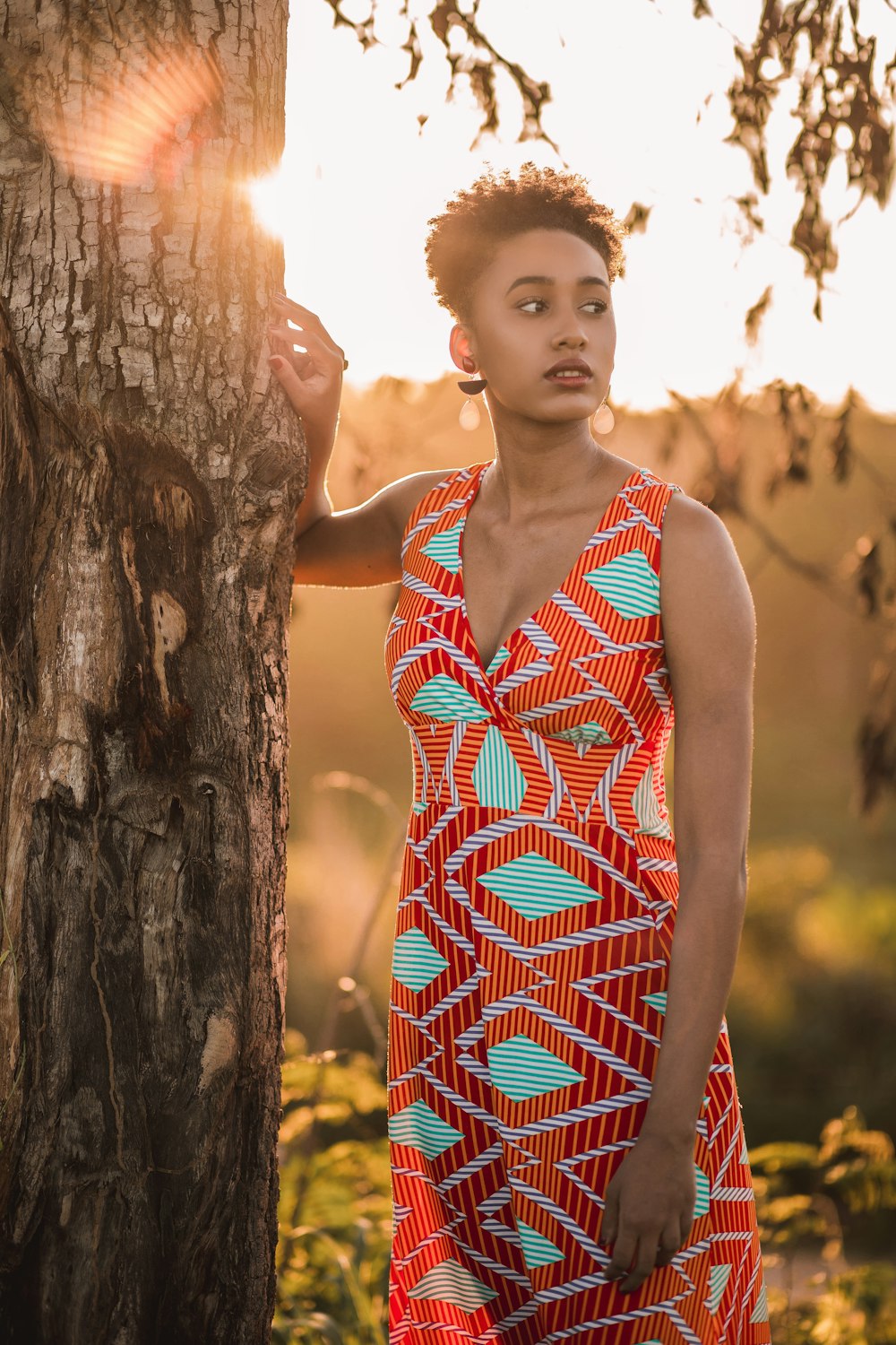 Mädchen in rot-weißen Tupfen ärmelloses Kleid, das tagsüber neben einem braunen Baum steht