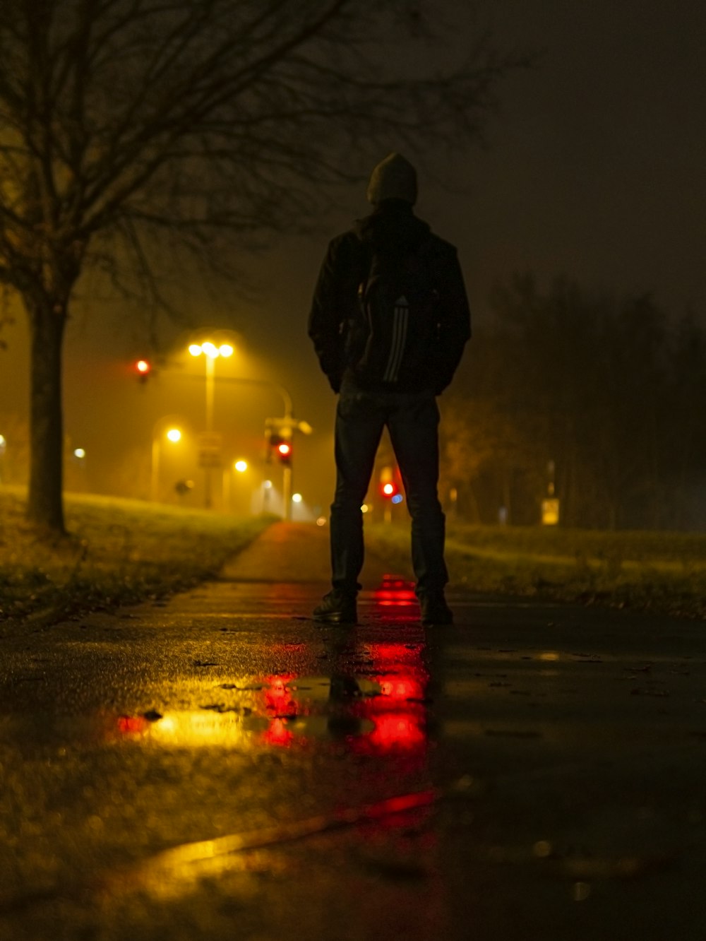 homem em jaqueta preta em pé na estrada durante a noite